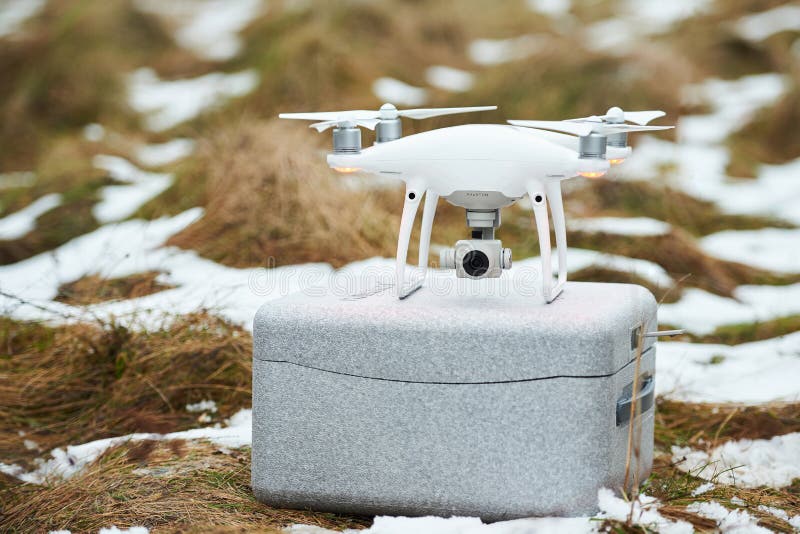 Minsk, Belarus - December 3, 2017: DJI phantom 4 pro drone stay on gray carry box on grown with snow. Minsk, Belarus - December 3, 2017: DJI phantom 4 pro drone stay on gray carry box on grown with snow