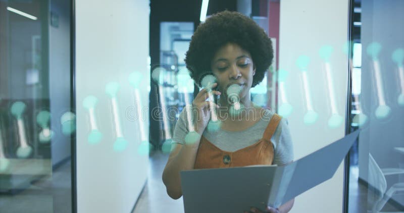 Dna structure spinning against african american woman talking on smartphone and walking at office royalty free stock photos