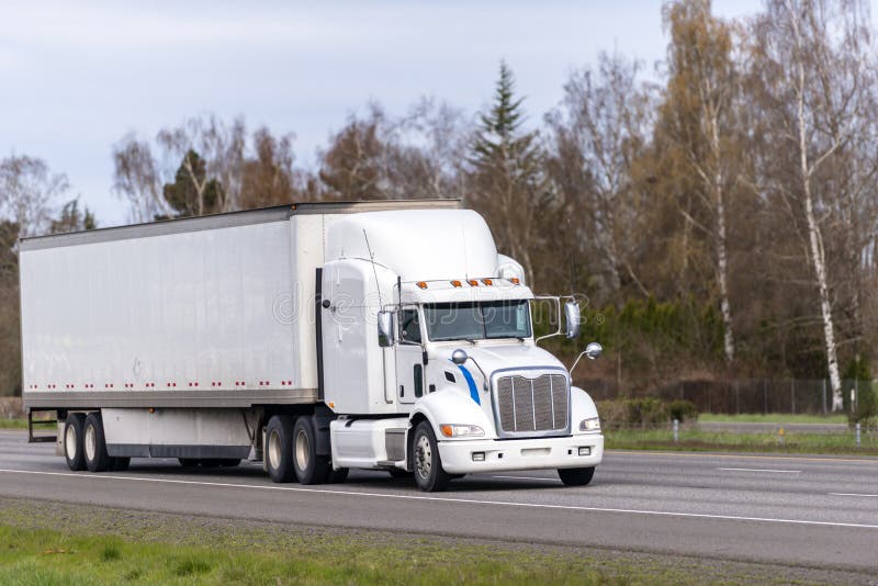 Do longo-curso do equipamento caminhÃ£o grande branco semi que transporta bens no reboque seco da camionete semi que corre na est