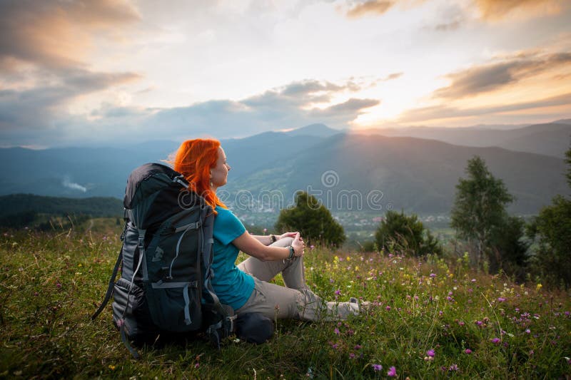 Doamnă roșcată cu rucsac în munți la apus royalty free stock photos