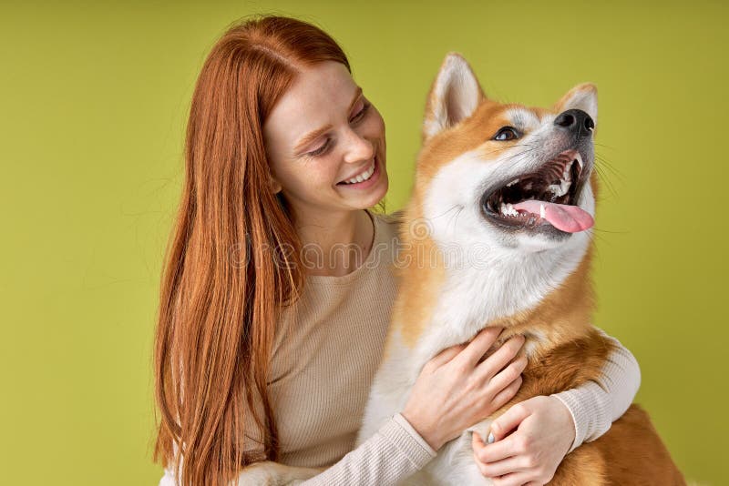 Doamnă roșcată fericită, îmbrăcată ocazional, câine de companie de rasă pură akita inu cu proprietar royalty free stock photos