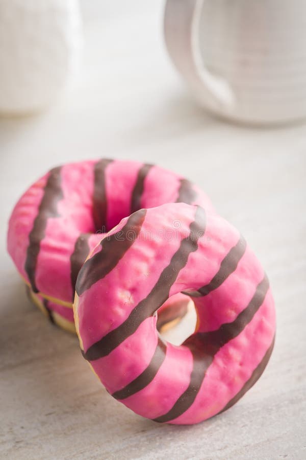 Doce donut cor-de-rosa com listras de chocolate em cima da mesa da cozinha foto de stock