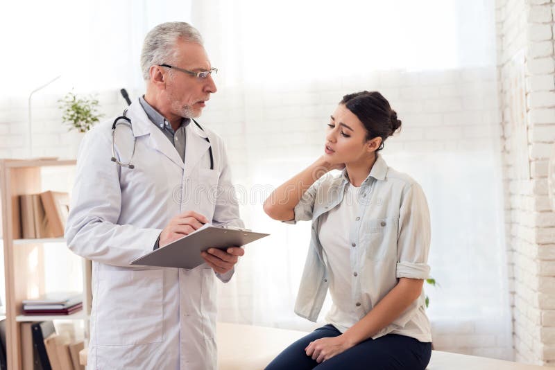 Docteur avec le stéthoscope et le patient féminin dans le bureau Maux patients de cou du ` s photos stock Docteur avec le stéthoscope et le patient féminin dans le bureau Maux patients de cou du ` s photos stock