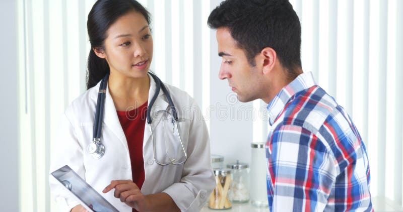 Docteur chinois expliquant le rayon X de cou au patient photographie stock libre de droits Docteur chinois expliquant le rayon X de cou au patient photographie stock libre de droits