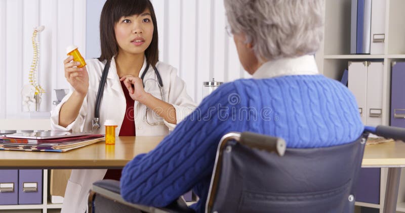 Docteur chinois parlant du médicament au patient plus âgé photos stock Docteur chinois parlant du médicament au patient plus âgé photos stock