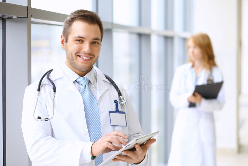 Docteur de sourire attendant son équipe tout en se tenant droit photos libres de droits Docteur de sourire attendant son équipe tout en se tenant droit photos libres de droits