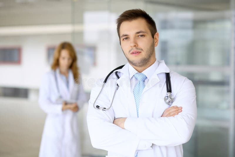 Docteur de sourire attendant son équipe tout en se tenant droit photo stock Docteur de sourire attendant son équipe tout en se tenant droit photo stock