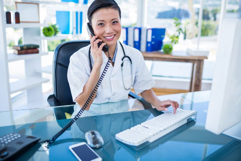 Download Docteur De Sourire Ayant L'appel Téléphonique Et à L'aide De Son Ordinateur Image stock - Image du composer, docteur: 56482211