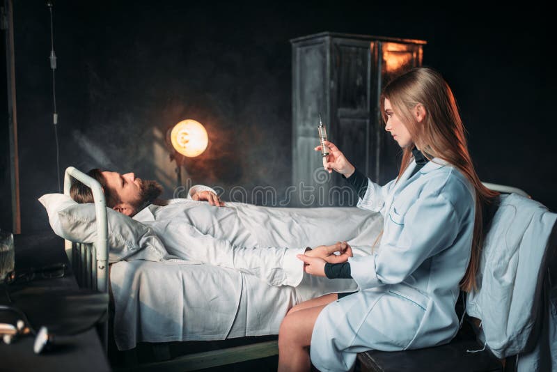 Docteur féminin avec la seringue contre le patient masculin photo libre de droits Docteur féminin avec la seringue contre le patient masculin photo libre de droits