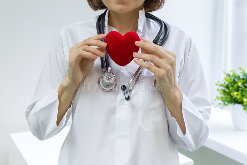 Docteur féminin avec le stéthoscope tenant le coeur, fenêtre d'hôpital de fond photographie stock libre de droits Docteur féminin avec le stéthoscope tenant le coeur, fenêtre d'hôpital de fond photographie stock libre de droits
