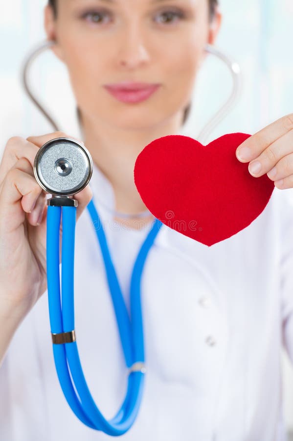 Docteur féminin avec le stéthoscope tenant le coeur rouge image libre de droits Docteur féminin avec le stéthoscope tenant le coeur rouge image libre de droits