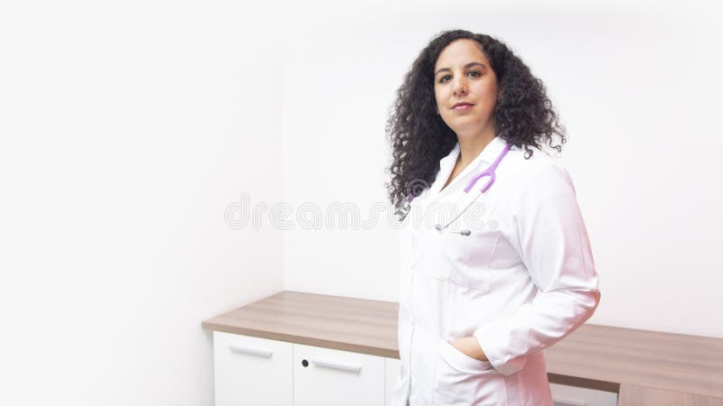Docteur féminin latin avec la position sérieuse d'attitude regardant la caméra dans son bureau avec le stéthoscope sur son cou photographie stock libre de droits Docteur féminin latin avec la position sérieuse d'attitude regardant la caméra dans son bureau avec le stéthoscope sur son cou photographie stock libre de droits