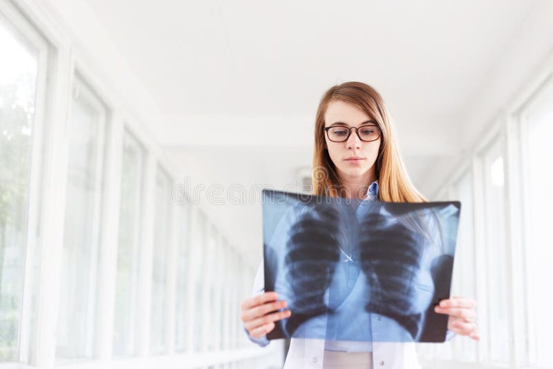 Docteur féminin sûr examinant exactement un rayon X de cage thoracique images stock Docteur féminin sûr examinant exactement un rayon X de cage thoracique images stock