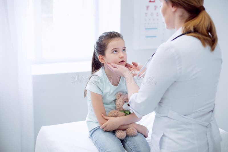 Docteur féminin vérifiant les amygdales bouleversées de filles photo libre de droits