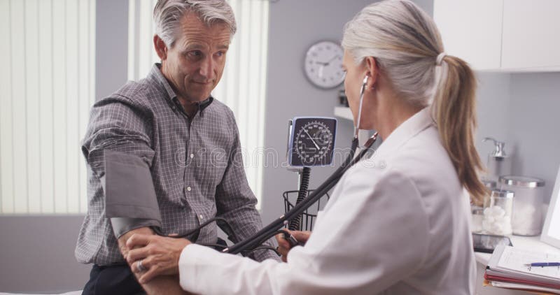 Docteur professionnel mesurant la tension artérielle d'homme supérieur photos stock Docteur professionnel mesurant la tension artérielle d'homme supérieur photos stock