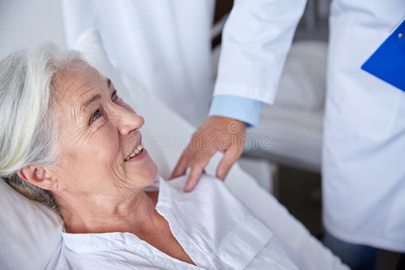 Docteur rendant visite à la femme supérieure heureuse à l'hôpital images libres de droits Docteur rendant visite à la femme supérieure heureuse à l'hôpital images libres de droits