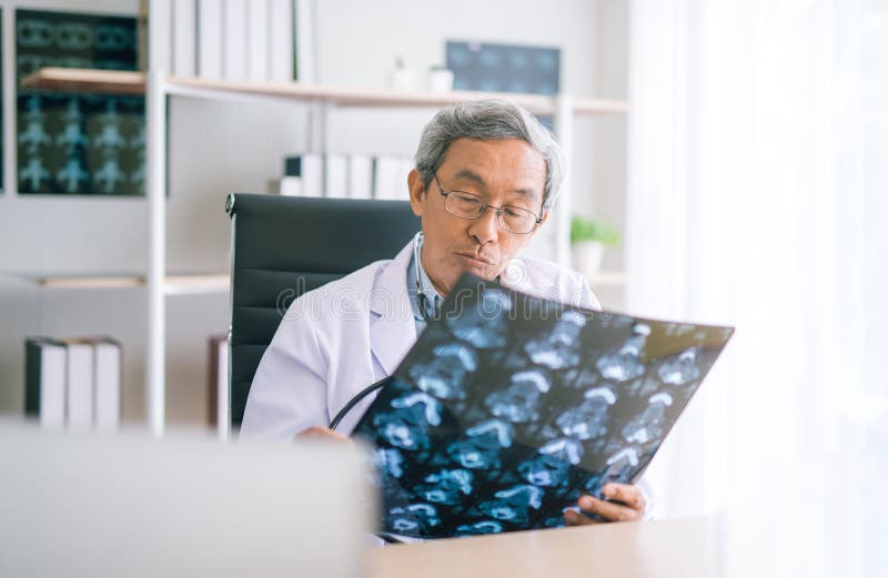 Docteur supérieur asiatique regardant le film de radiographie de la poitrine dans l'hôpital photos stock Docteur supérieur asiatique regardant le film de radiographie de la poitrine dans l'hôpital photos stock