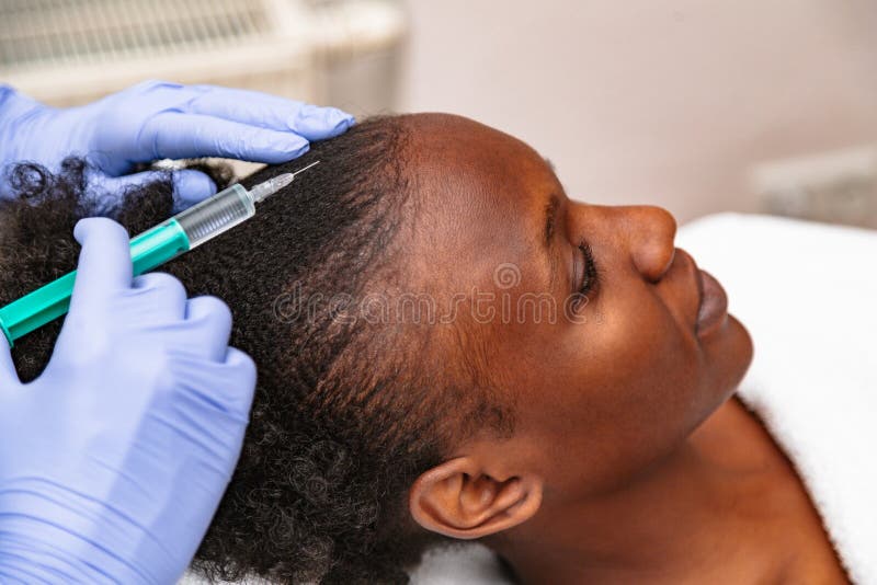 Doctor aesthetician makes head beauty injections to a female african patient