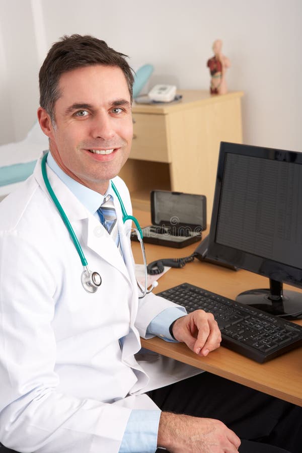 Doctor americano que se sienta en el escritorio fotos de archivo libres de regalías Doctor americano que se sienta en el escritorio fotos de archivo libres de regalías