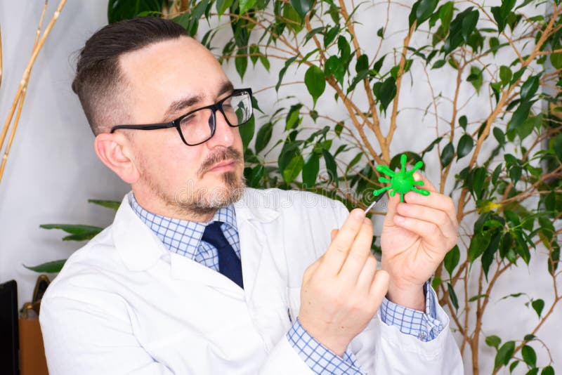 Doctor at appointment or scientist microbiologist virologist shows model of microorganism - virus prion or bacteria. Demonstration royalty free stock photography