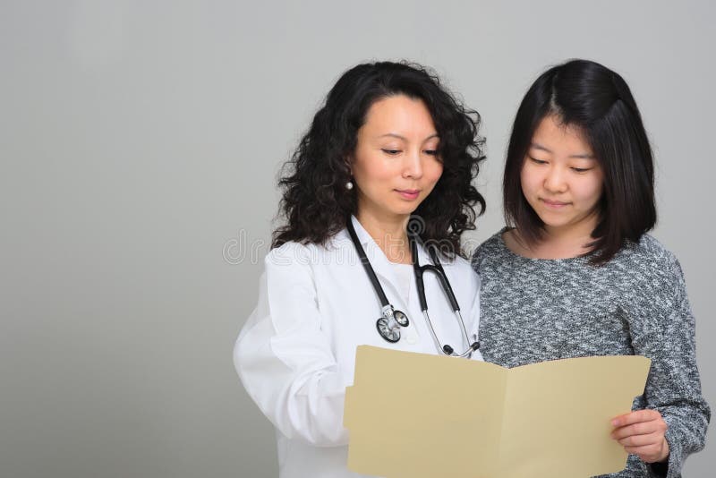 Doctor asiático de sexo femenino con el paciente femenino y la carta médica imágenes de archivo libres de regalías Doctor asiático de sexo femenino con el paciente femenino y la carta médica imágenes de archivo libres de regalías