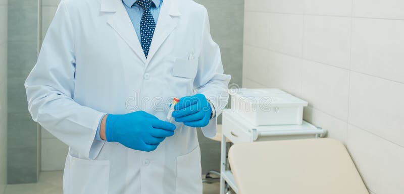 Test tube for analysis in the hands of a doctor. Preparation for sampling. A doctor in blue gloves is holding an empty tube for testing.