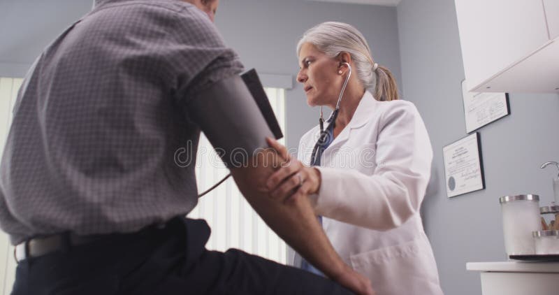 Doctor checking blood pressure of middle-aged male patient stock image Doctor checking blood pressure of middle-aged male patient stock image