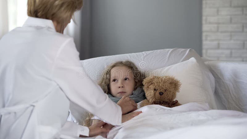 Doctor checking heart and lungs of scared girl with stethoscope in hospital royalty free stock photo Doctor checking heart and lungs of scared girl with stethoscope in hospital royalty free stock photo
