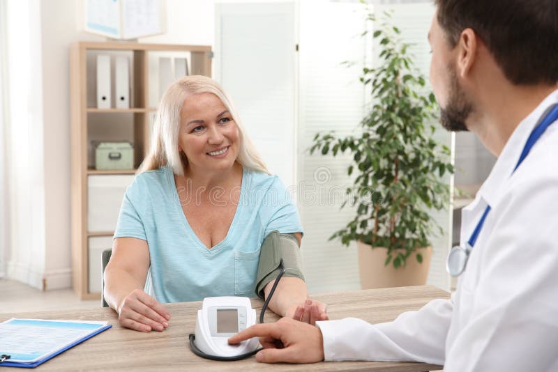 Doctor checking mature woman`s pulse with medical device royalty free stock photo Doctor checking mature woman`s pulse with medical device royalty free stock photo