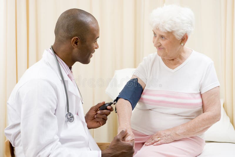 Doctor checking woman's blood pressure stock images