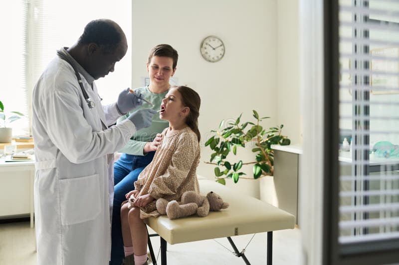 Doctor Examining Child with Parent in Medical Office stock photos