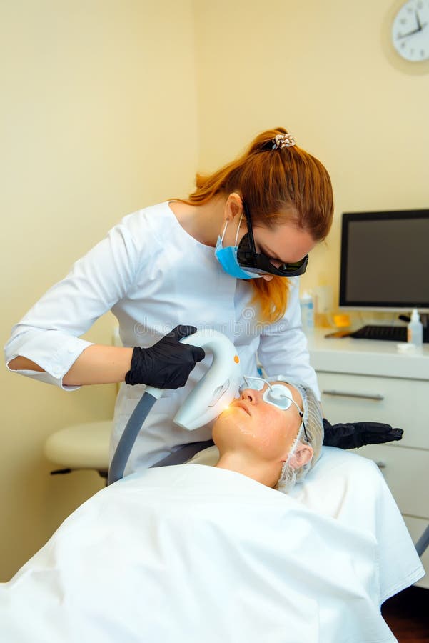 Doctor conducts procedure for rejuvenating facial skin with laser. Woman receiving facial beauty treatment, removing pigmentation stock images