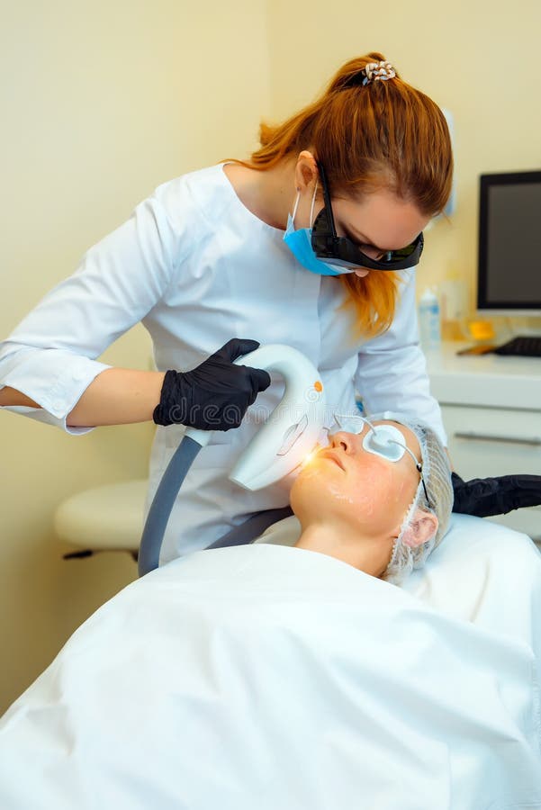 Doctor conducts procedure for rejuvenating facial skin with laser. Woman receiving facial beauty treatment, removing pigmentation stock photos