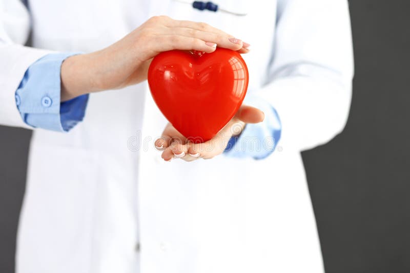 Doctor de sexo femenino con el estetoscopio que lleva a cabo el coraz?n en sus brazos Concepto de la atenci?n sanitaria y de la c fotografía de archivo Doctor de sexo femenino con el estetoscopio que lleva a cabo el coraz?n en sus brazos Concepto de la atenci?n sanitaria y de la c fotografía de archivo