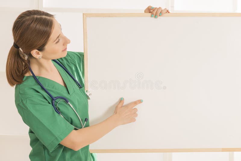 Doctor de sexo femenino hermoso joven sonriente feliz que muestra el área en blanco para la muestra o el copyspace foto de archivo libre de regalías Doctor de sexo femenino hermoso joven sonriente feliz que muestra el área en blanco para la muestra o el copyspace foto de archivo libre de regalías