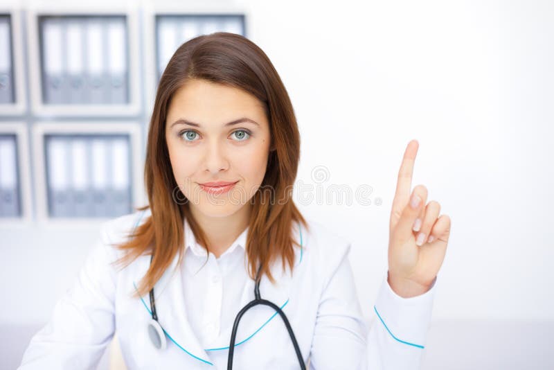 Doctor de sexo femenino joven con un dedo aumentado fotografía de archivo libre de regalías Doctor de sexo femenino joven con un dedo aumentado fotografía de archivo libre de regalías
