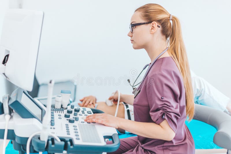 Doctor de sexo femenino joven del londe con los vidrios negros Esc?ner del ultrasonido en las manos de un doctor diagn?stico Sono foto de archivo libre de regalías Doctor de sexo femenino joven del londe con los vidrios negros Esc?ner del ultrasonido en las manos de un doctor diagn?stico Sono foto de archivo libre de regalías