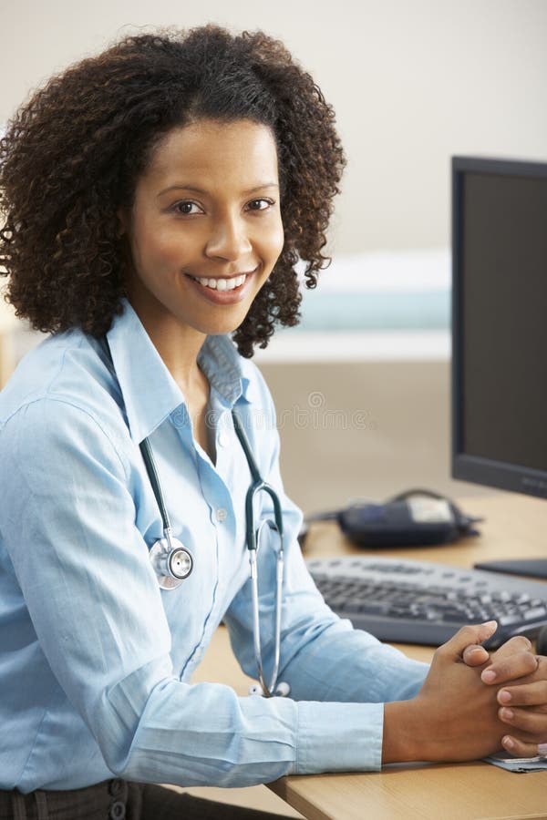 Doctor de sexo femenino joven que se sienta en el escritorio foto de archivo libre de regalías Doctor de sexo femenino joven que se sienta en el escritorio foto de archivo libre de regalías
