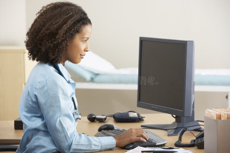 Doctor de sexo femenino joven que trabaja en el ordenador en el escritorio foto de archivo Doctor de sexo femenino joven que trabaja en el ordenador en el escritorio foto de archivo