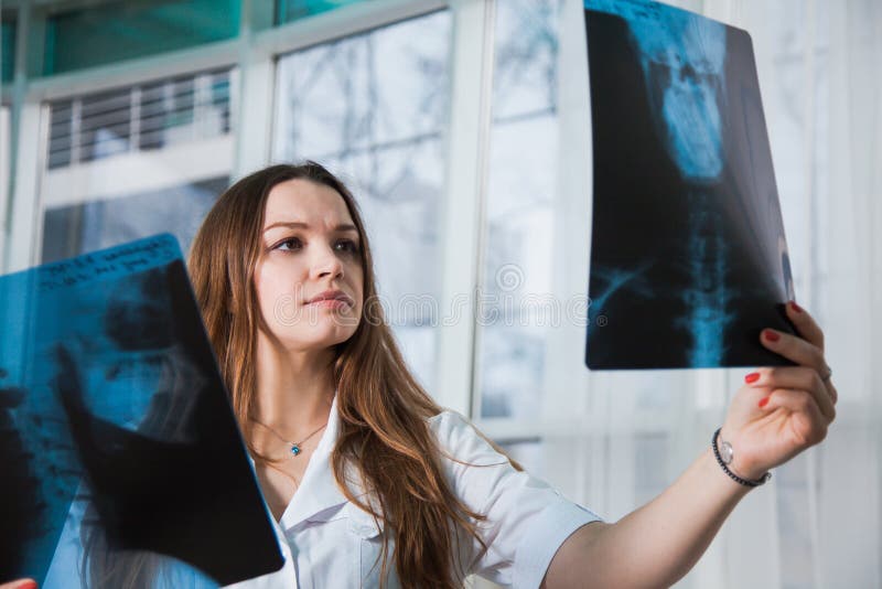 Doctor de sexo femenino profesional joven que examina la radiografía paciente del ` s fotos de archivo libres de regalías Doctor de sexo femenino profesional joven que examina la radiografía paciente del ` s fotos de archivo libres de regalías