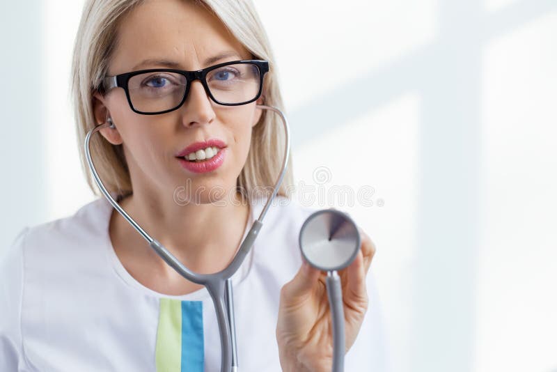 Doctor de sexo femenino que escucha con el estetoscopio fotos de archivo Doctor de sexo femenino que escucha con el estetoscopio fotos de archivo