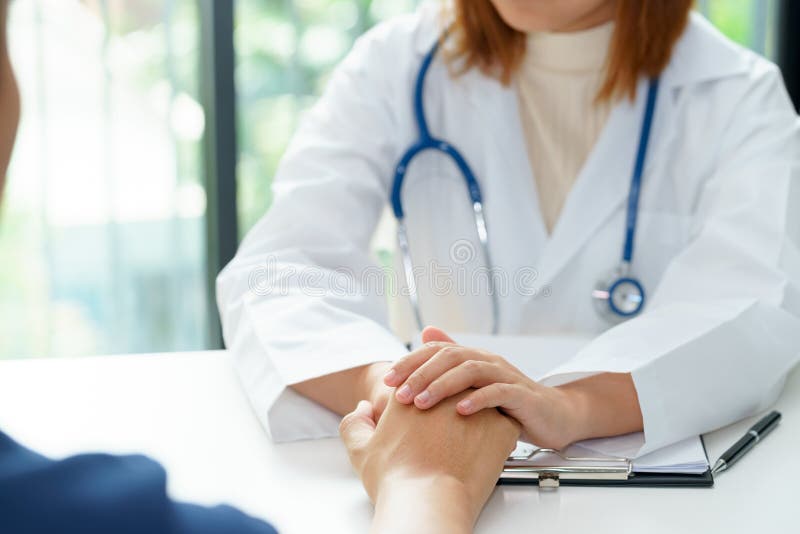 Doctor de sexo femenino que lleva a cabo las manos pacientes para alegre foto de archivo libre de regalías Doctor de sexo femenino que lleva a cabo las manos pacientes para alegre foto de archivo libre de regalías