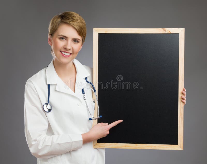 Doctor de sexo femenino sonriente que lleva a cabo al tablero negro. fotos de archivo libres de regalías Doctor de sexo femenino sonriente que lleva a cabo al tablero negro. fotos de archivo libres de regalías