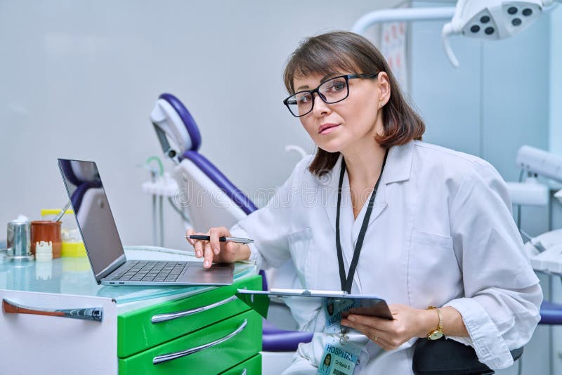 Doctor Dentist Working in Office, Using Laptop, Making Notes on