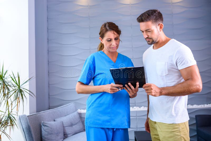 A Doctor discussing details of a medical procedure with a handsome male Patientr. A Doctor discussing details of a medical procedure with a handsome male Patientr