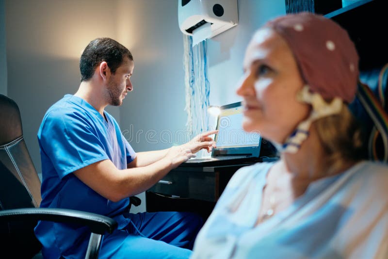 Doctor performing EEG exam to old women in hospital laboratory. Physician doing brain therapy on senior lady in clinic. Lab worker using equipment on ill elderly patient. Doctor performing EEG exam to old women in hospital laboratory. Physician doing brain therapy on senior lady in clinic. Lab worker using equipment on ill elderly patient.