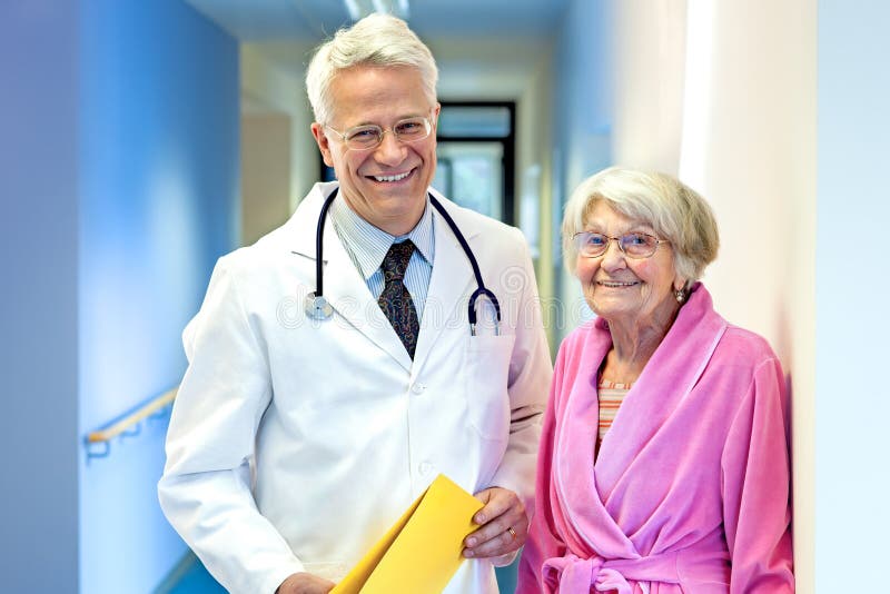 Smiling Doctor with Elderly Patient Smiling in hospital corridor. Standing file folder stock images, royalty-free photos and pictures