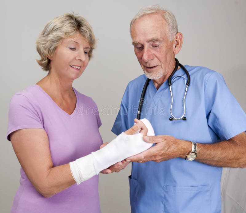 Doctor examining cast on senior woman s arm