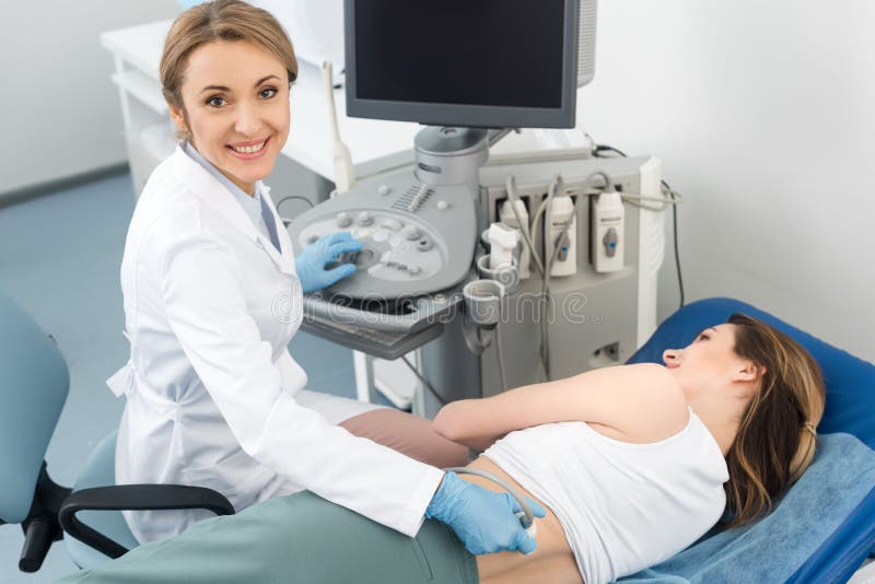 Smiling doctor examining kidney of female patient with ultrasound scan in clinic