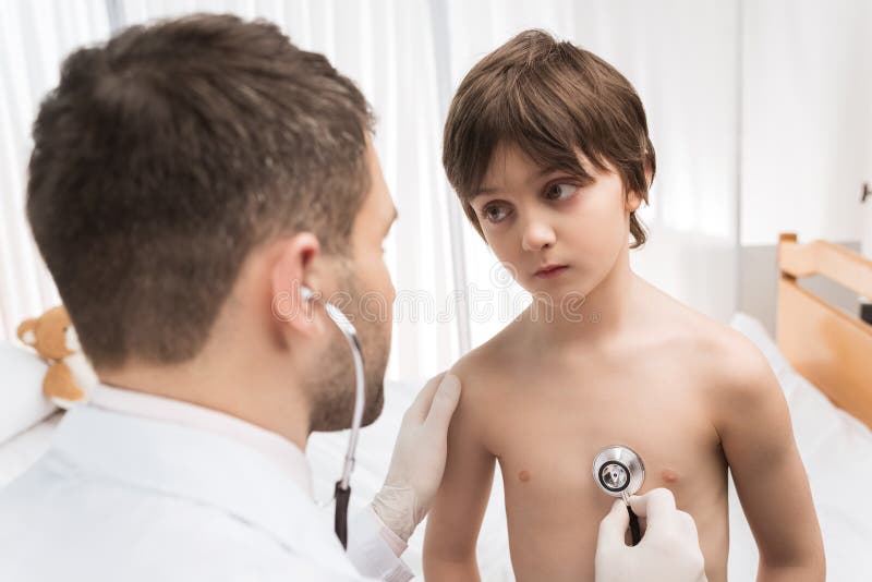 Doctor examining little boy with stethoscope in hospital